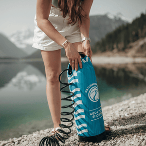 Nahaufnahme der Campingdusche von Naturbummler. Im Hintergrund befindet sich ein See