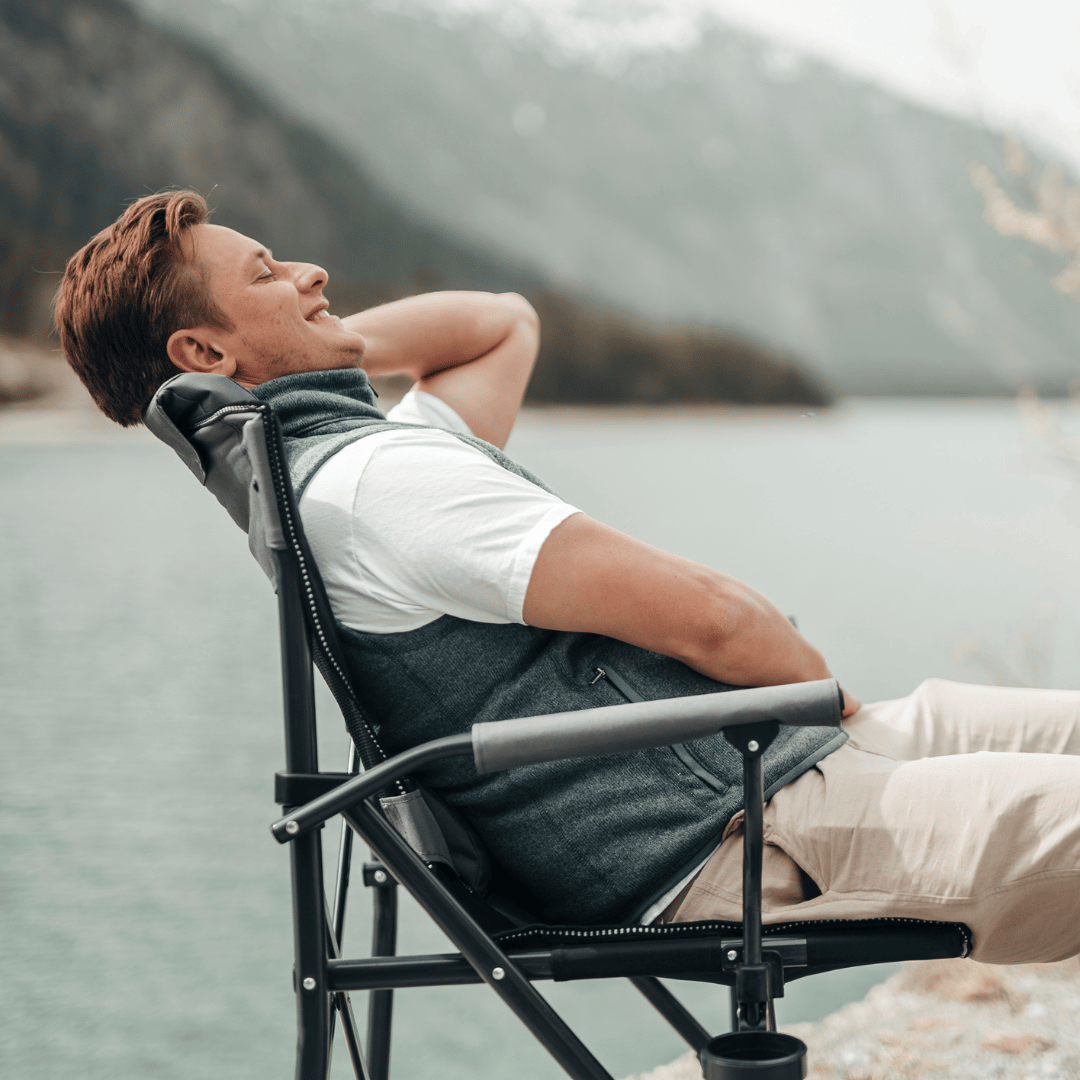 Seitliche Aufnahme eines lächelnden jungen Mannes, der in einem Campingstuhl sitzt. 